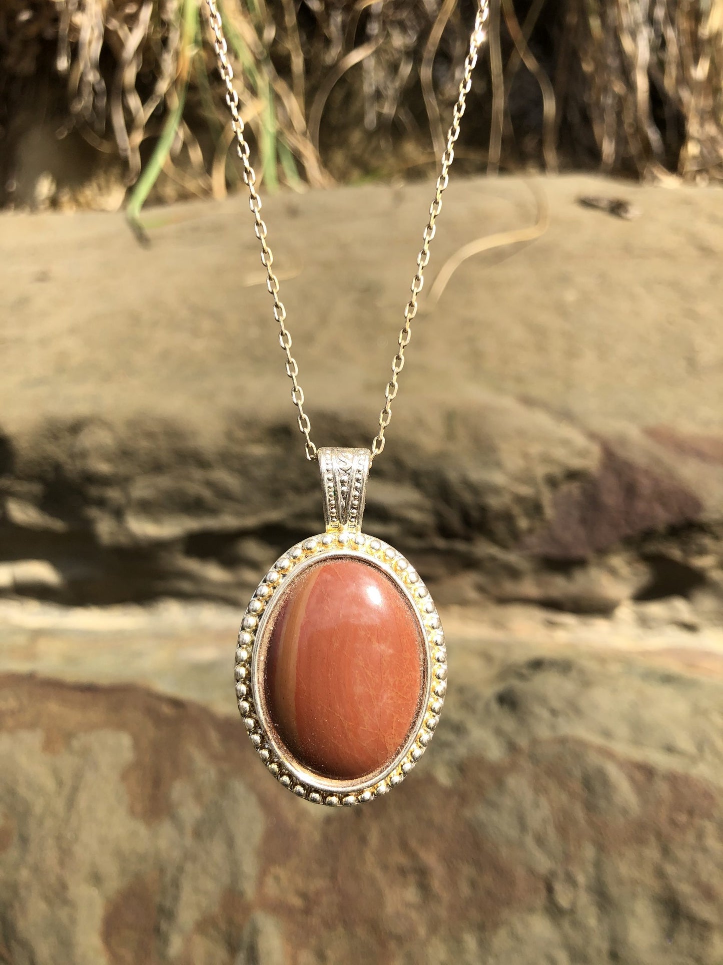 Necklace of Petrified Wood, turned to Jasper, with red and orange hues, from Coromandel, New Zealand, hand polished to a 30x22mm cabochon and set in a silver plated setting with 19 inch chain, front