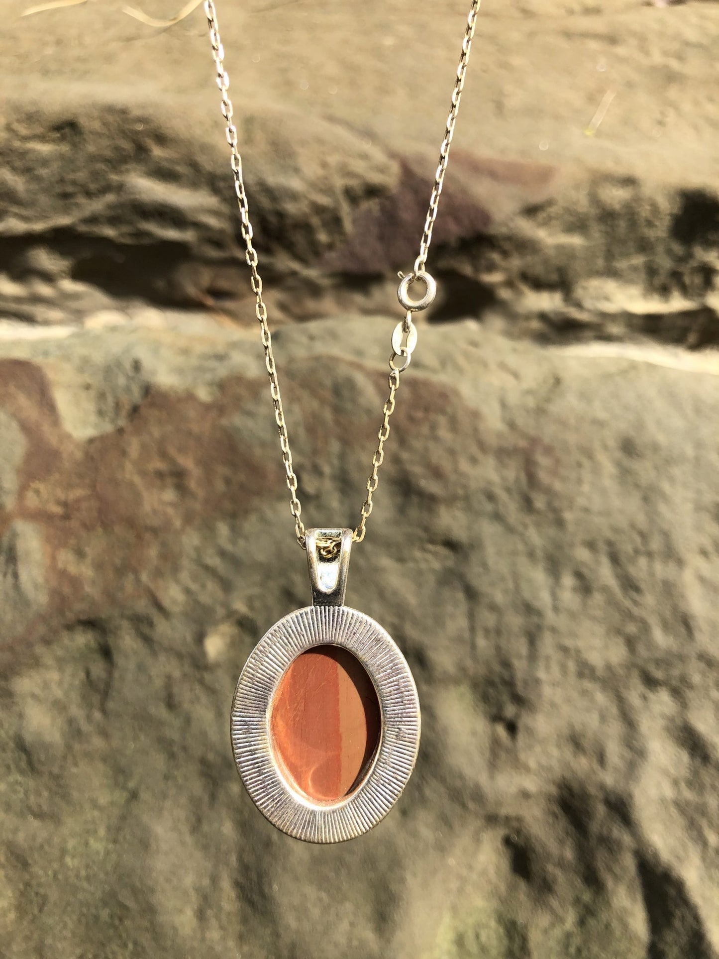 Necklace of Petrified Wood, turned to Jasper, with red and orange hues, from Coromandel, New Zealand, hand polished to a 30x22mm cabochon and set in a silver plated setting with 19 inch chain, back