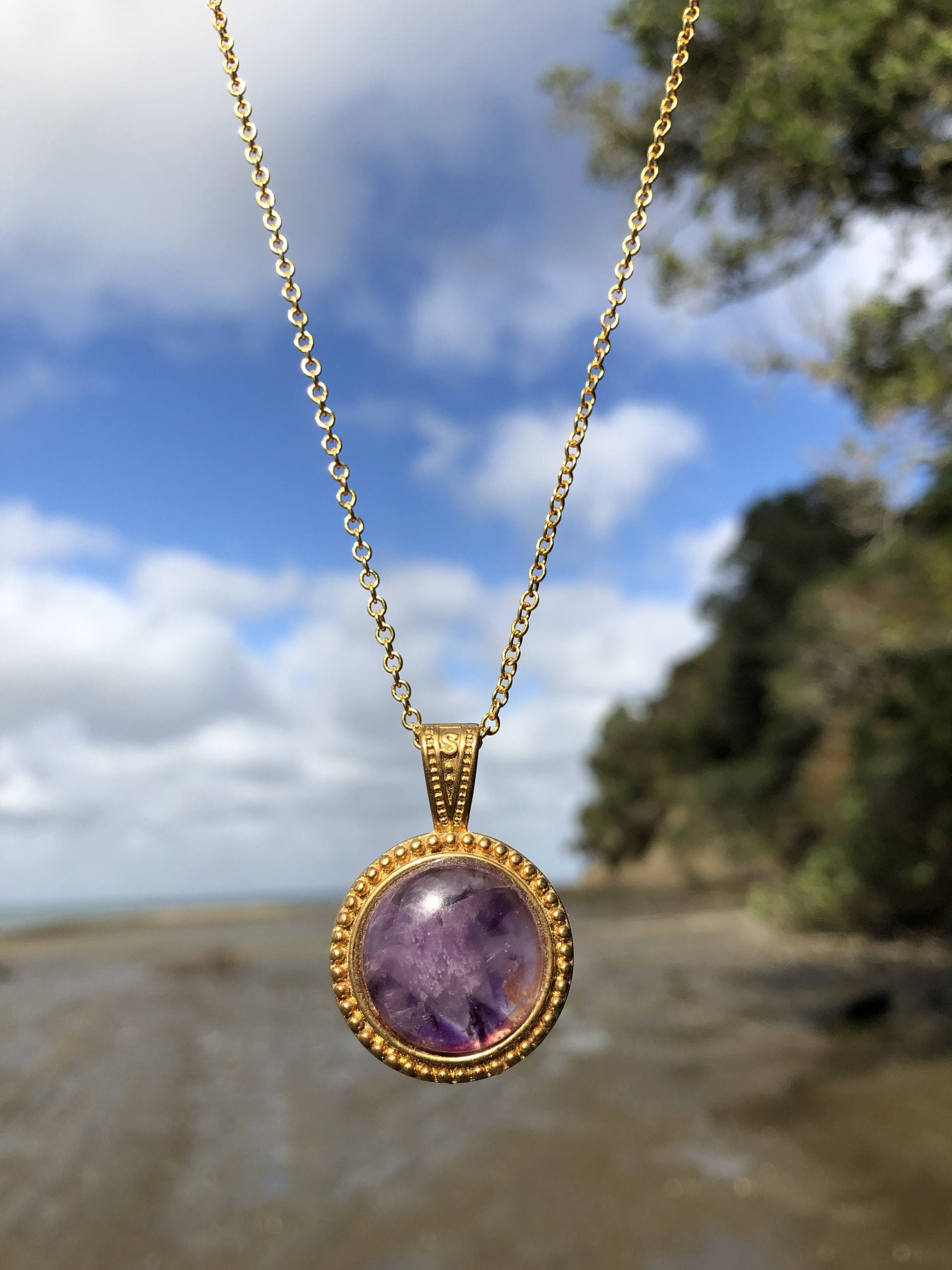 Necklace with beautiful purple Amethyst with natural color variations from crystal growth, hand polished to a 18mm round cabochon and set in a gold-plated setting with 19 inch chain, front