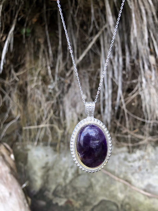 Necklace with rich, dark purple Amethyst, hand polished to a 30x22mm oval cabochon and set in a silver-plated setting with 19 inch chain on beach grass
