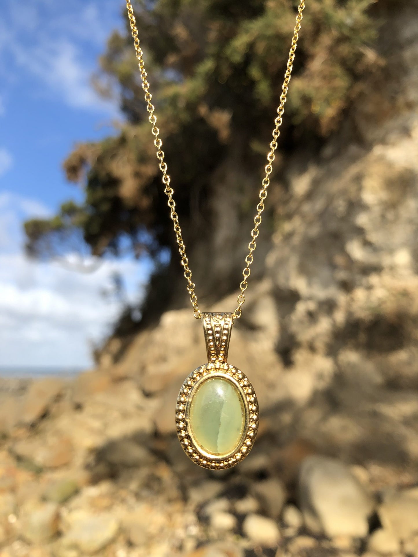 Necklace with Botswana Jade (green aventurine), hand polished to a 14x10mm cabochon and set in a gold-plated setting with 19 inch chain, on beach