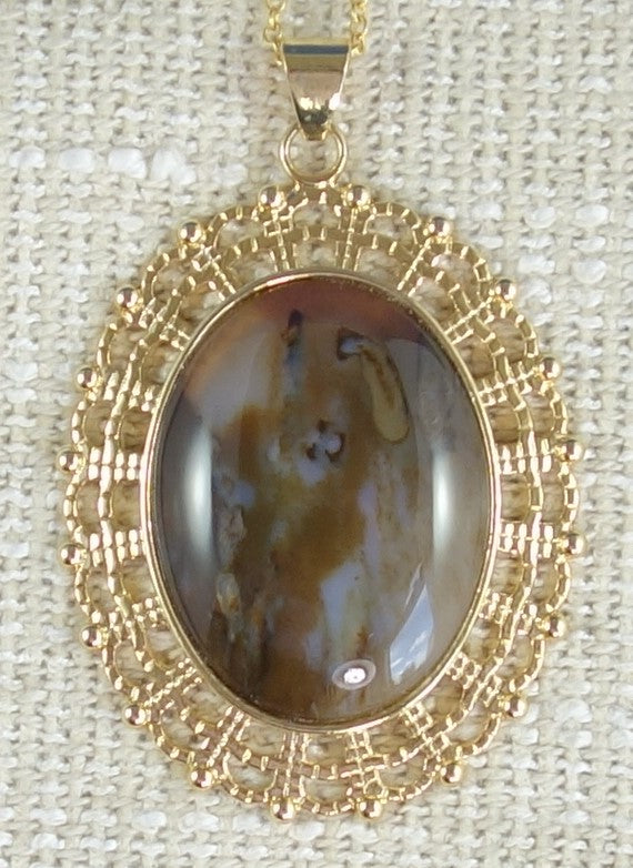 Necklace of petrified wood from Table Mountain, Kauranga Valley New Zealand with rich brown, yellow, black and white figuring. The stone is hand cut into a 40x30mm cabochon and set in a gold plated setting with 19 inch chain.