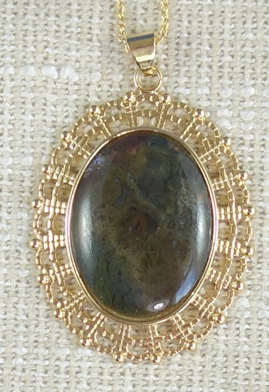 Necklace with Indian moss agate with thick green moss including some earthy brown highlights creating what look like flowers in clear agate matrix, hand polished into a 40x30mm cabochon and set in a gold plated setting with 19 inch chain.