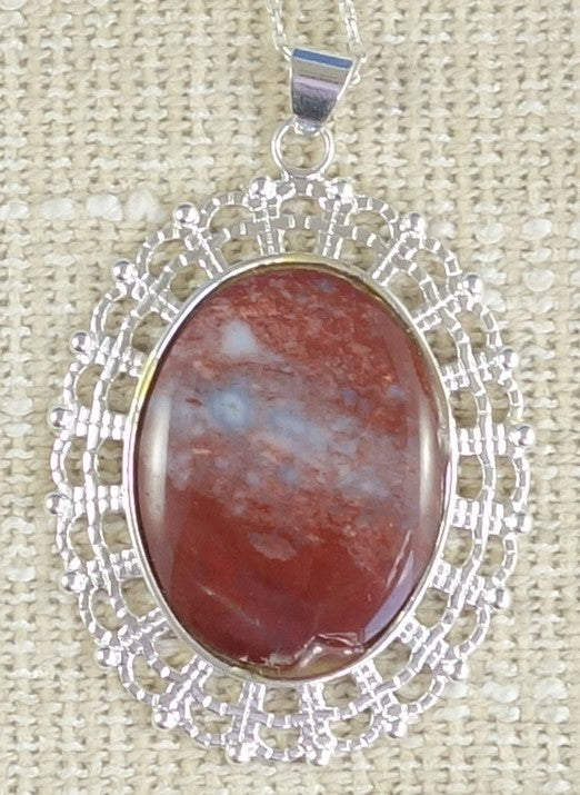 Necklace with large red jasper with a milky way of blue chalcedony running across it, collected from the Hotoritori stream in Coromandel New Zealand, hand polished into a 40x30mm cabochon and set in a silver plated setting with 19 inch chain.