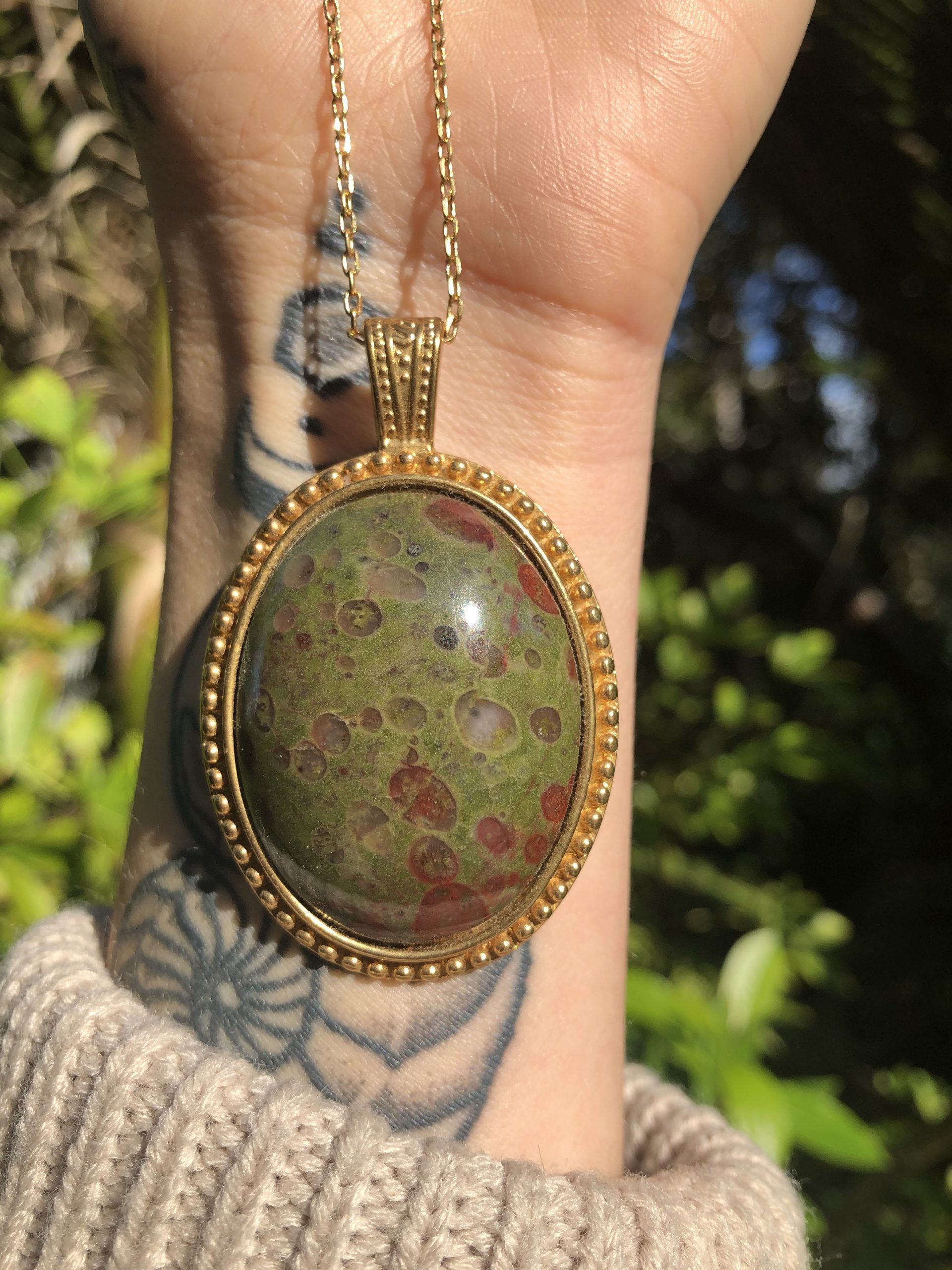 Necklace with rare New Zealand reverse poppy jasper with red poppy dots on a background of green jasper, hand polished into a 40x30mm cabochon and set into a gold plated setting with 19 inch chain - held