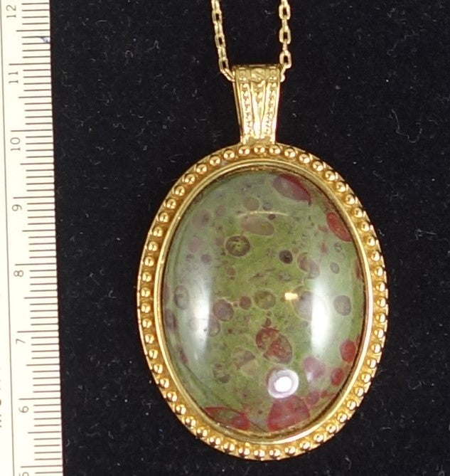 Necklace with rare New Zealand reverse poppy jasper with red poppy dots on a background of green jasper, hand polished into a 40x30mm cabochon and set into a gold plated setting with 19 inch chain - on black