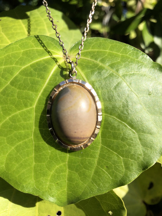 Necklace with a natural wonder stone chert from Coromandel New Zealand with subtle patterns of greys, tans and browns. This stone is hand polished in a 25x18mm cabochon and set in a silver-plated setting with a 19 inch chain.