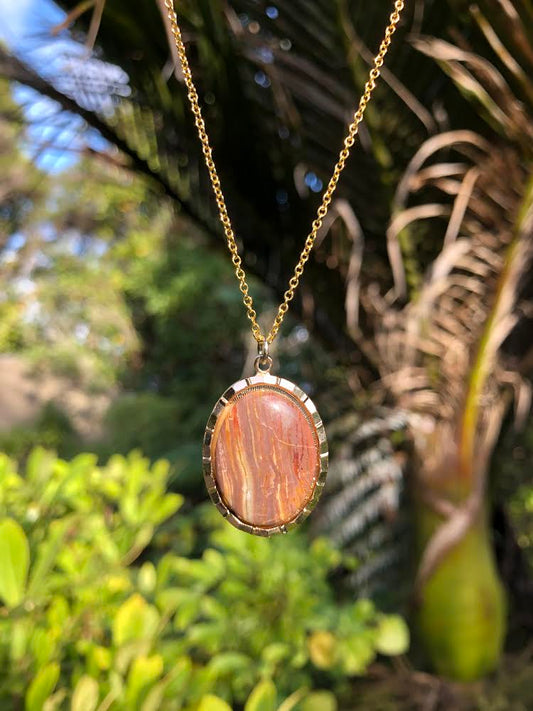 Necklace with natural New Zealand Rhyolite with mauve-purple, tan and cream stripes, hand polished to a 25x18mm cabochon and set in a gold plated setting with 19 inch chain.