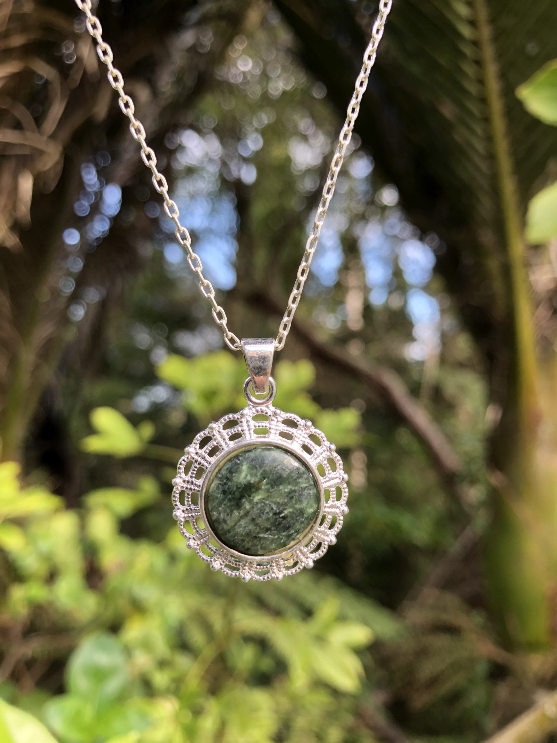 Necklace with New Zealand Pounamu (Greenstone, nephrite jade), dark green with lovely markings, hand polished to a 14mm round cabochon and mounted in a silver plated setting with 19 inch chain.