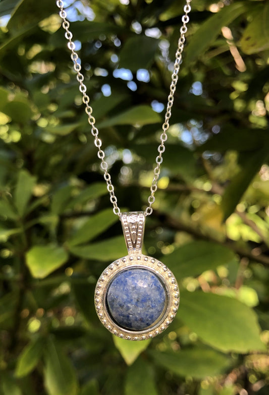 Necklace of natural blue quartz from Brazil, hand polished to a 14mm round cabochon and set in a silver plated setting with 19 inch chain.