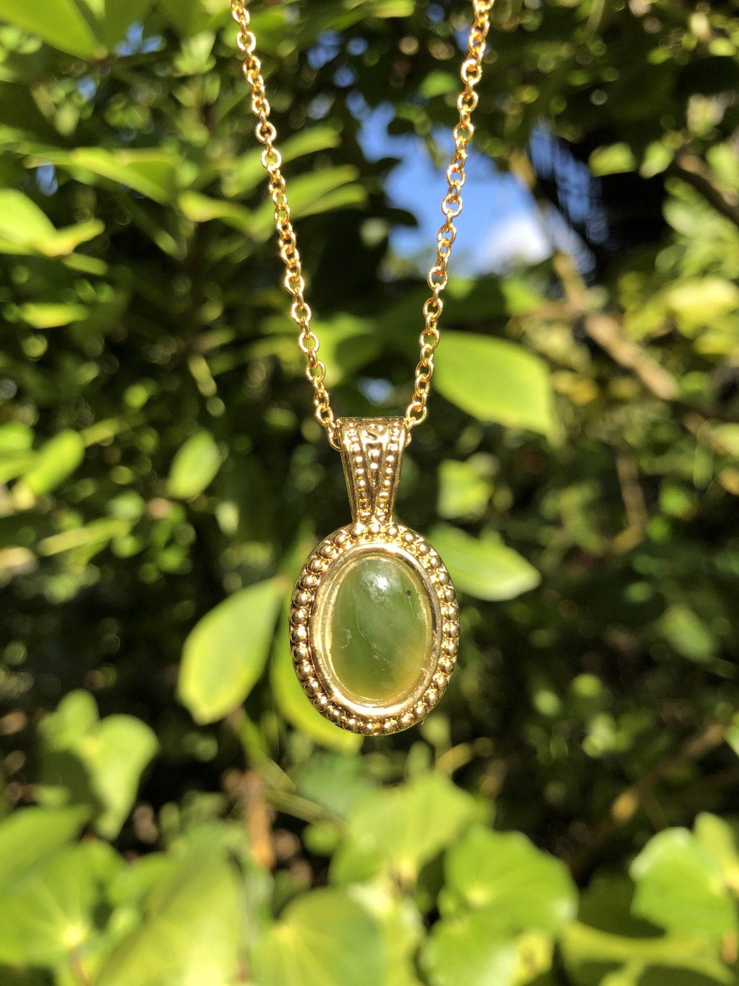 Necklace with New Zealand Pounamu (Greenstone, nephrite jade), bright green Kahurangi jade, hand polished to an 14x10mm cabochon and mounted in a gold plated setting with 19 inch chain.