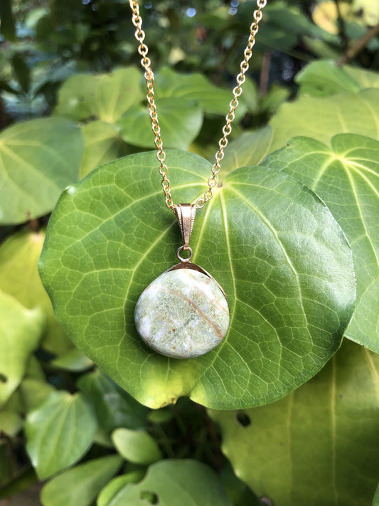 Necklace of a natural riverstone of green serpentine in white quartz, about 22mm round, tumble polished and set in a gold plated setting with 19 inch chain.