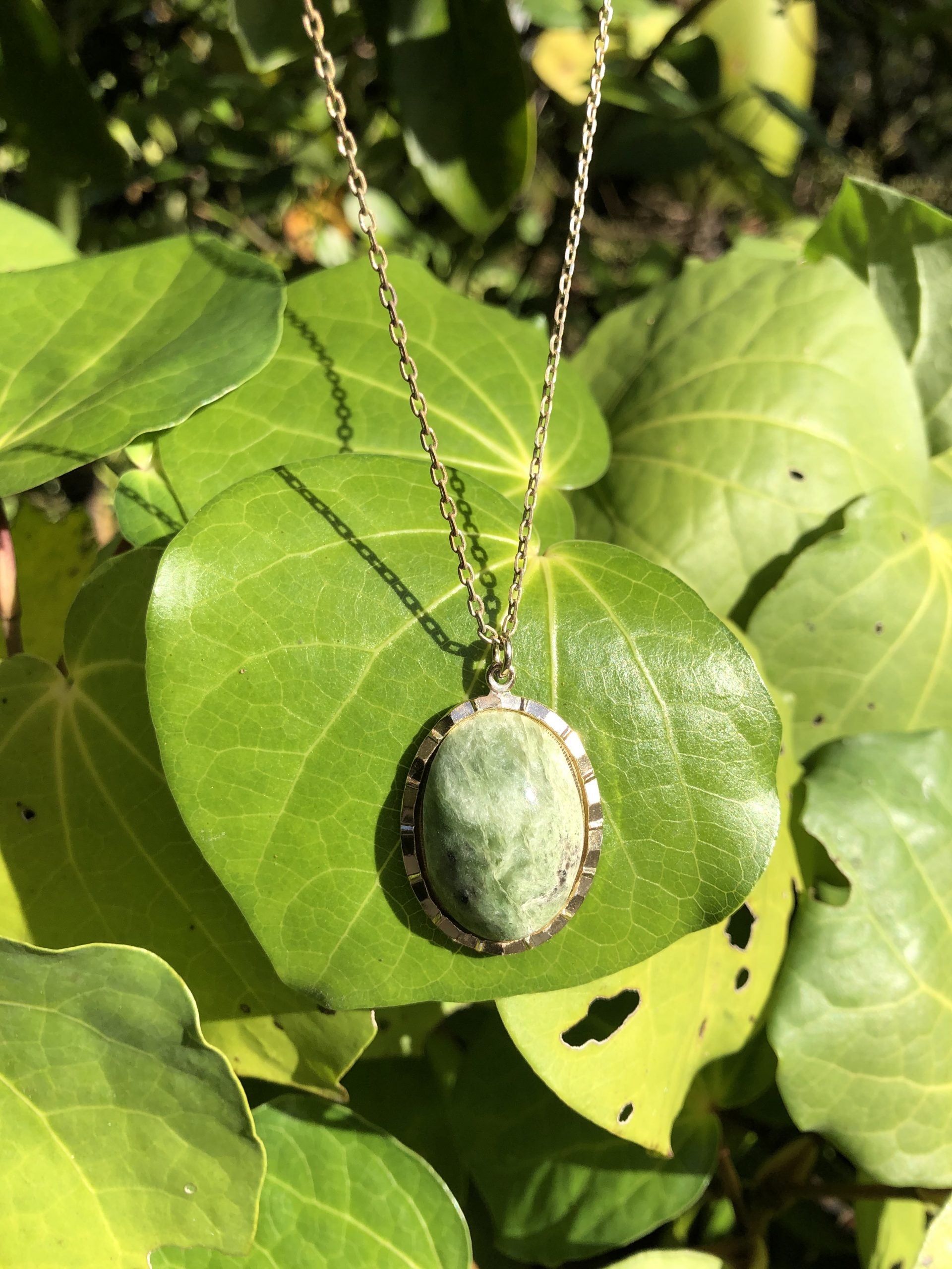 Necklace with natural New Zealand serpentine, green with subtle markings, hand polished to a 25x18mm cabochon and set in a gold plated setting with 19 inch chain, on leaf