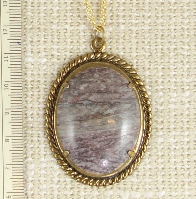 Necklace of banded purple rhyolite from Coromandel New Zealand, hand cut into a 40x30mm cabochon and set in gold plated setting with 19 inch chain.