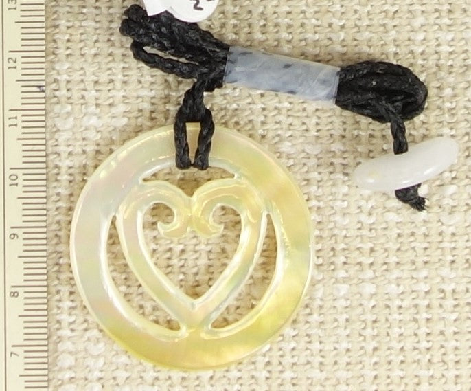 Necklace of hand carved and polished mother of pearl with a koru-heart in a torus, tied with a hand braided string with white quartz toggle. This piece is creamy white with rainbows of pearlescent pinks, greens, blues and yellows shimmering through - on burlap