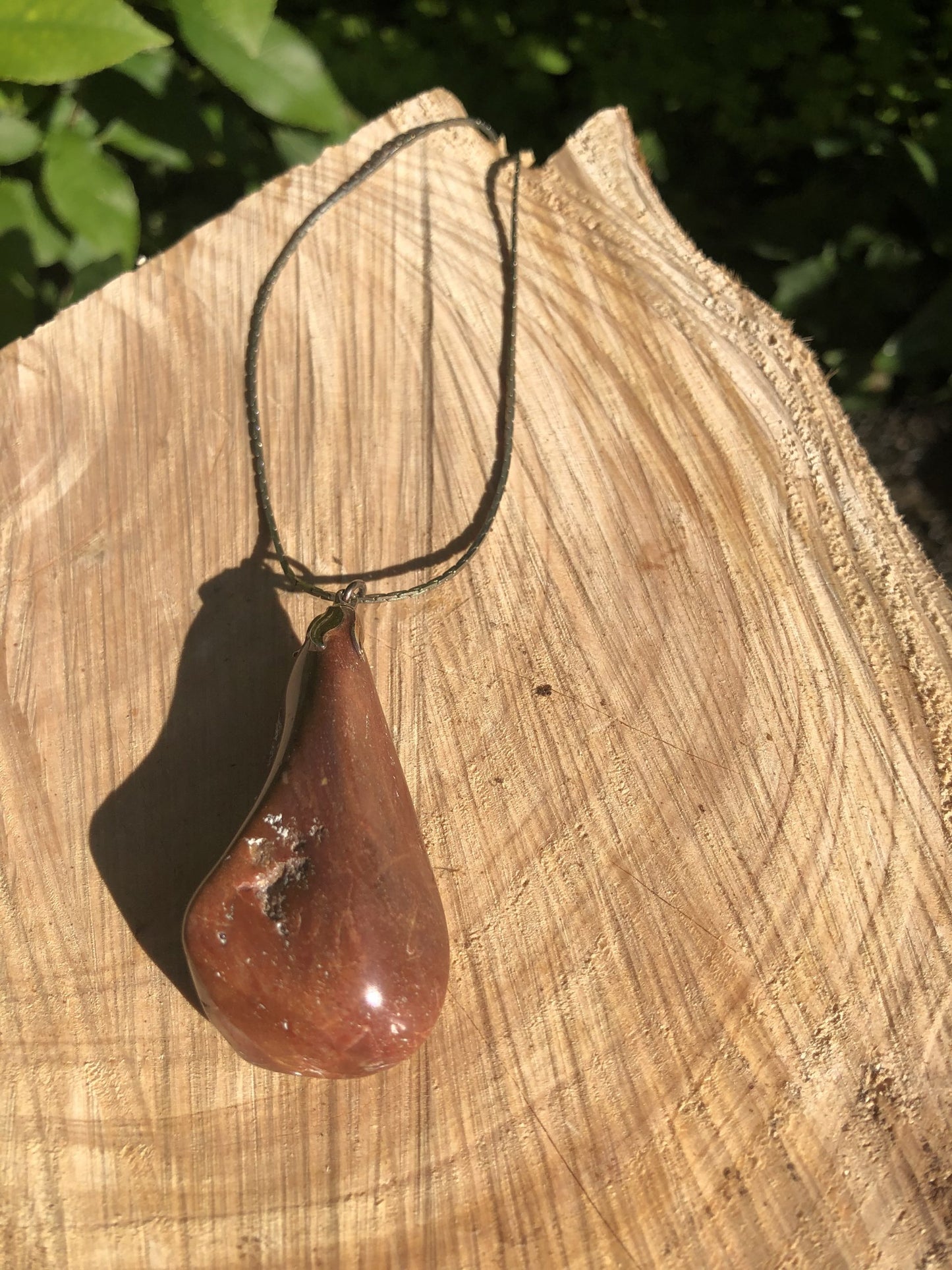 Necklace with a unique red jasperized wood (petrified to jasper), found on a beach on Western Coromandel and tumble polished to a 47mm long idiosyncratic drop, mounted with a gold plated bell cap, with a 19 inch chain, on log