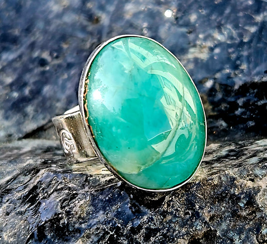 A rich green Aventurine, hand cut and polished to an 18x13mm cabochon and set in a sterling silver, adjustable ring, front.