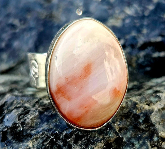 A strong and subtle New Zealand petrified wood, hand cut and polished to an 18x13mm cabochon and set in a sterling silver, adjustable ring, front.