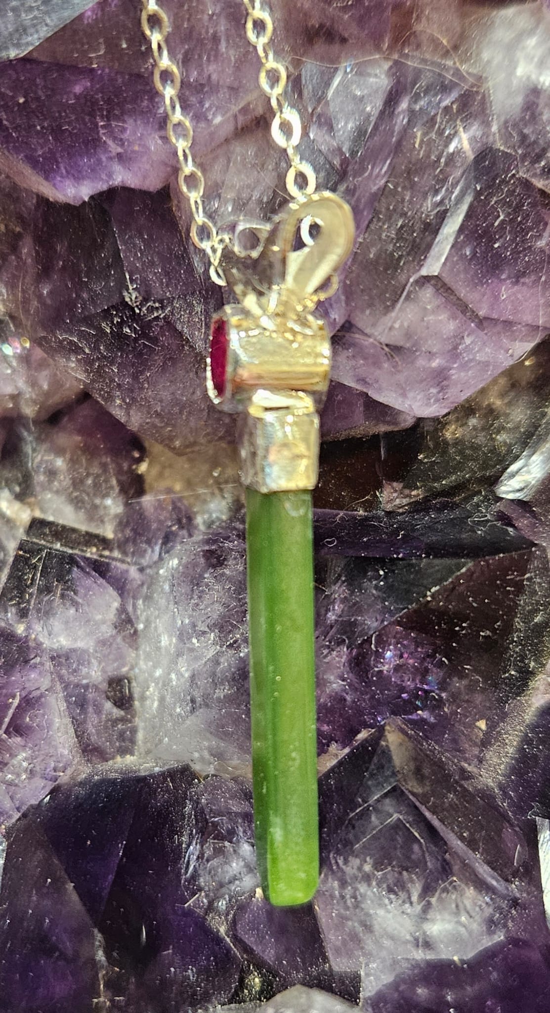 Necklace with bright, apple green Kahurangi Pounamu drop, 25mm long with a bright red lab-grown real 5mm ruby, side.
