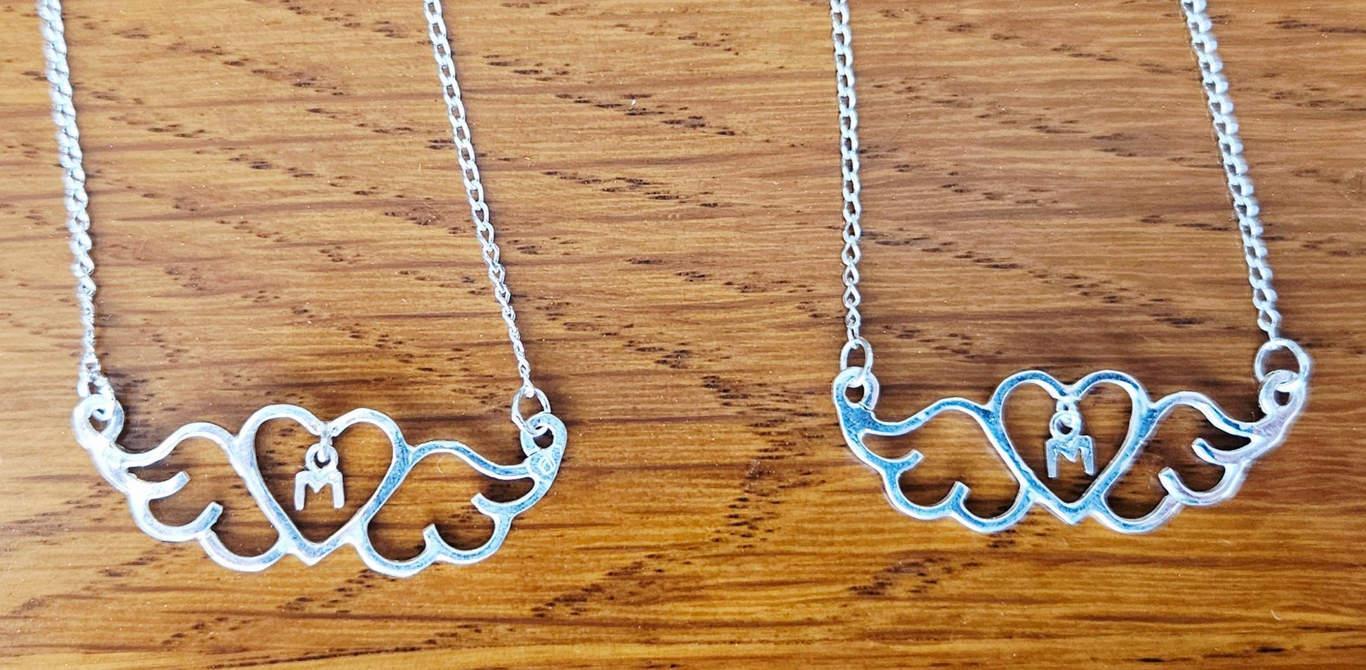 Small (40mm wide) Heart-Wing pendant with a letter "M" charm, for Mother, all in solid sterling silver and a solid sterling silver chain. This is a perfect Mother's Day gift, 2 on wood.